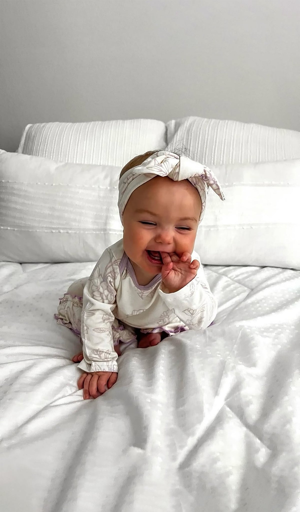 Bali Ruffle Romper 2-Piece worn by baby girl sitting on a bed.