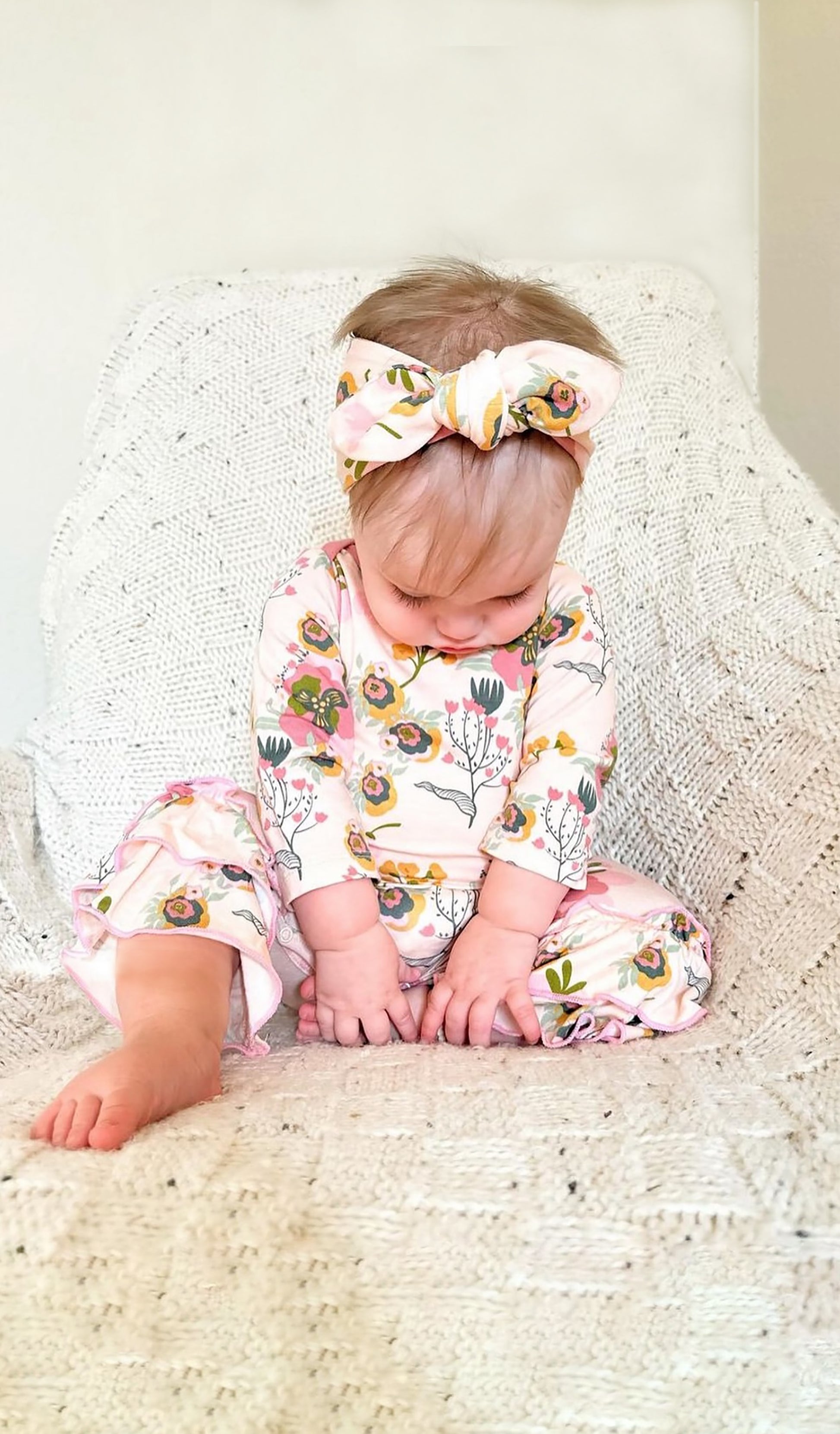 Ruffle Romper 2 Piece - Camellia worn by baby girl sitting on knit blanket.