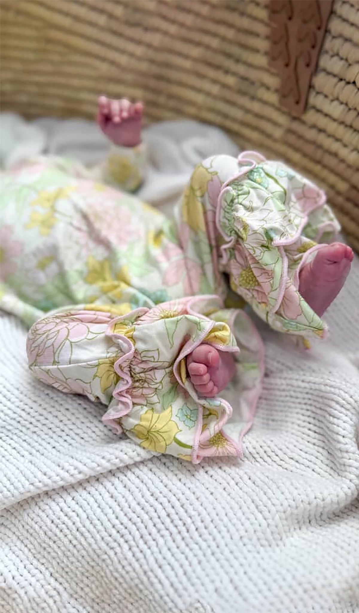 Floral Begonia patterned baby outfit with pink accents worn by baby with little feet.