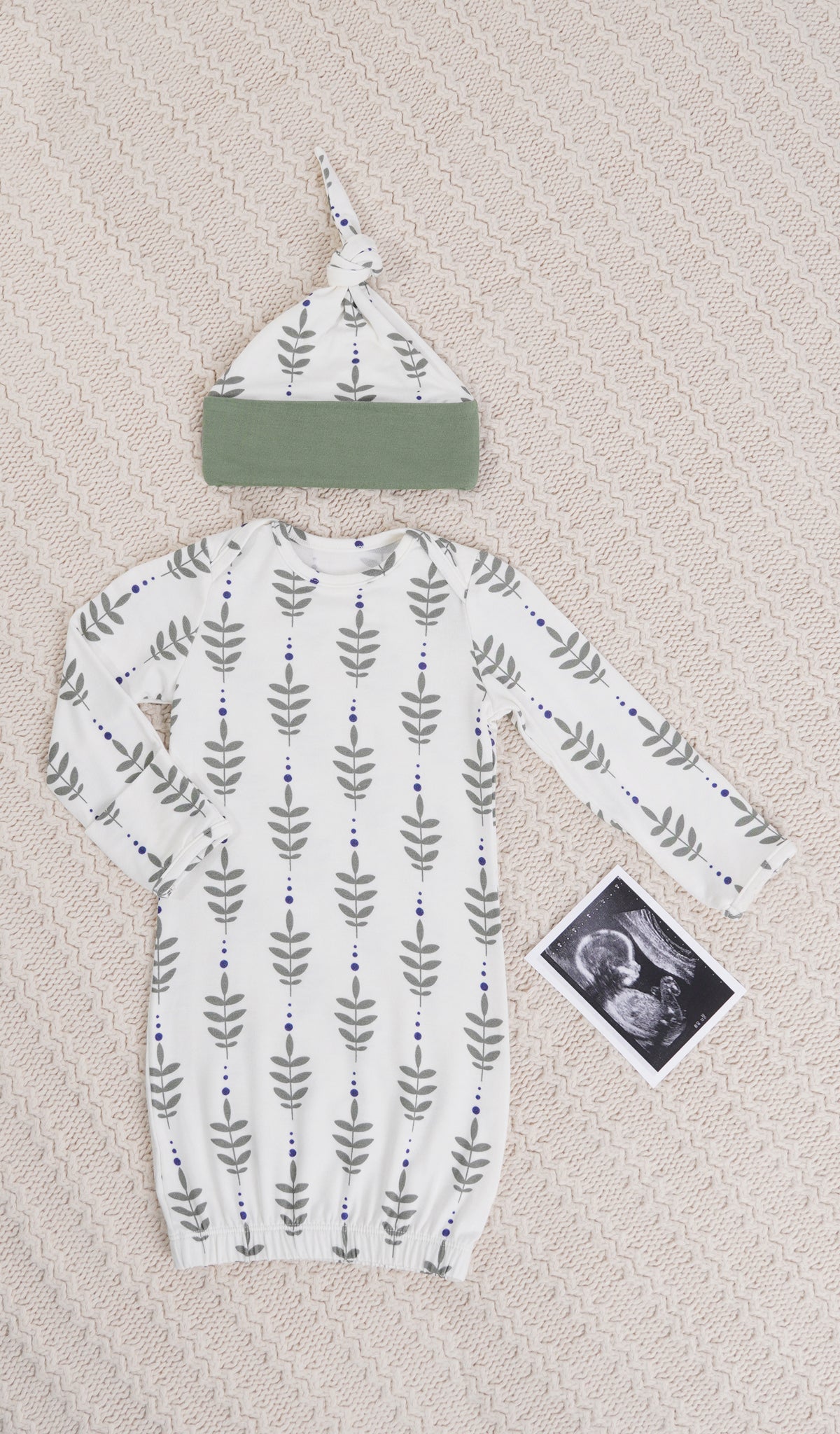 Eucalyptus Analise 5-Piece Set, gown and knotted hat for baby with ultrasound on a textured beige blanket.