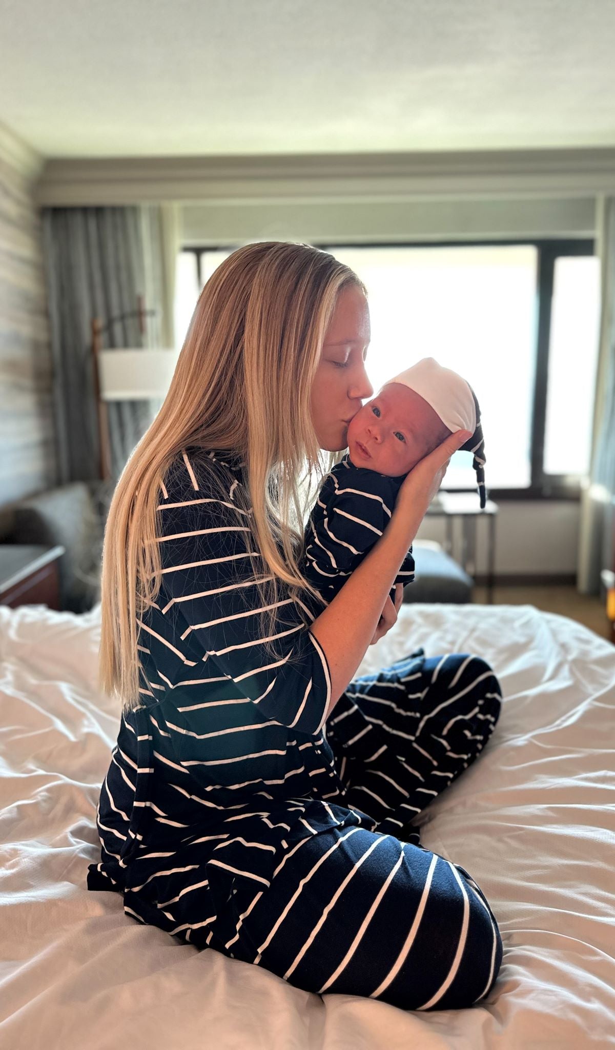 Navy Gown 2-Piece worn by baby being cuddled by his mom sitting on bed.