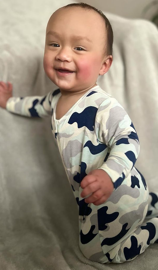 Camo Footie with long sleeves worn by smiling baby kneeling on a blanket.