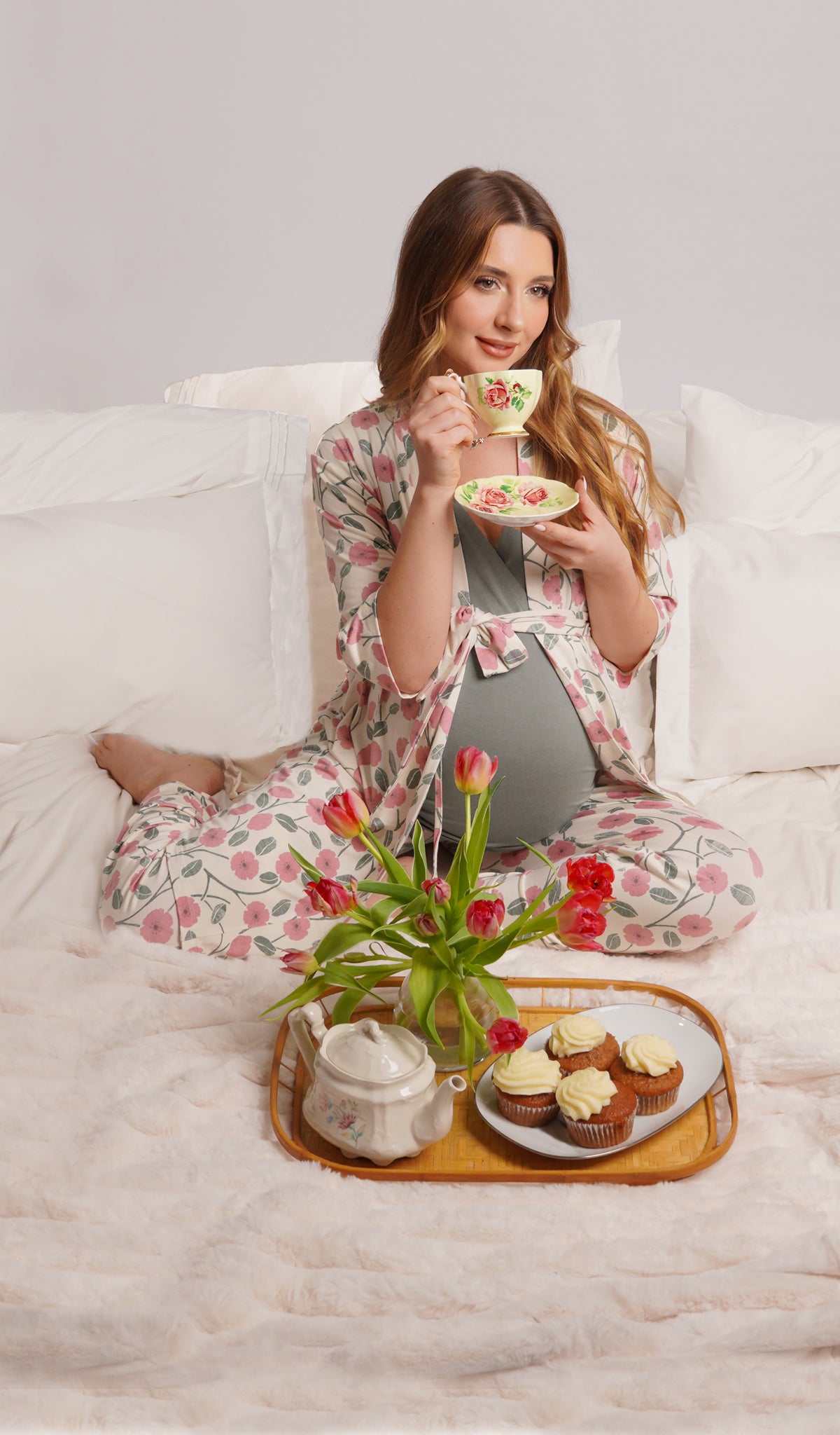Honey Bloom Analise 3-Piece Set, woman wearing robe, tank top and pant while sitting on a bed making drinking tea with muffins.