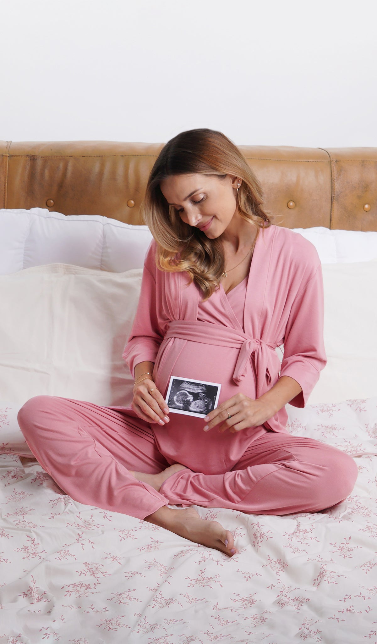 Rose Analise 3-Piece Set, woman wearing robe, tank top and pant sitting cross legged on a bed and holding an ultrasound in front of her belly.