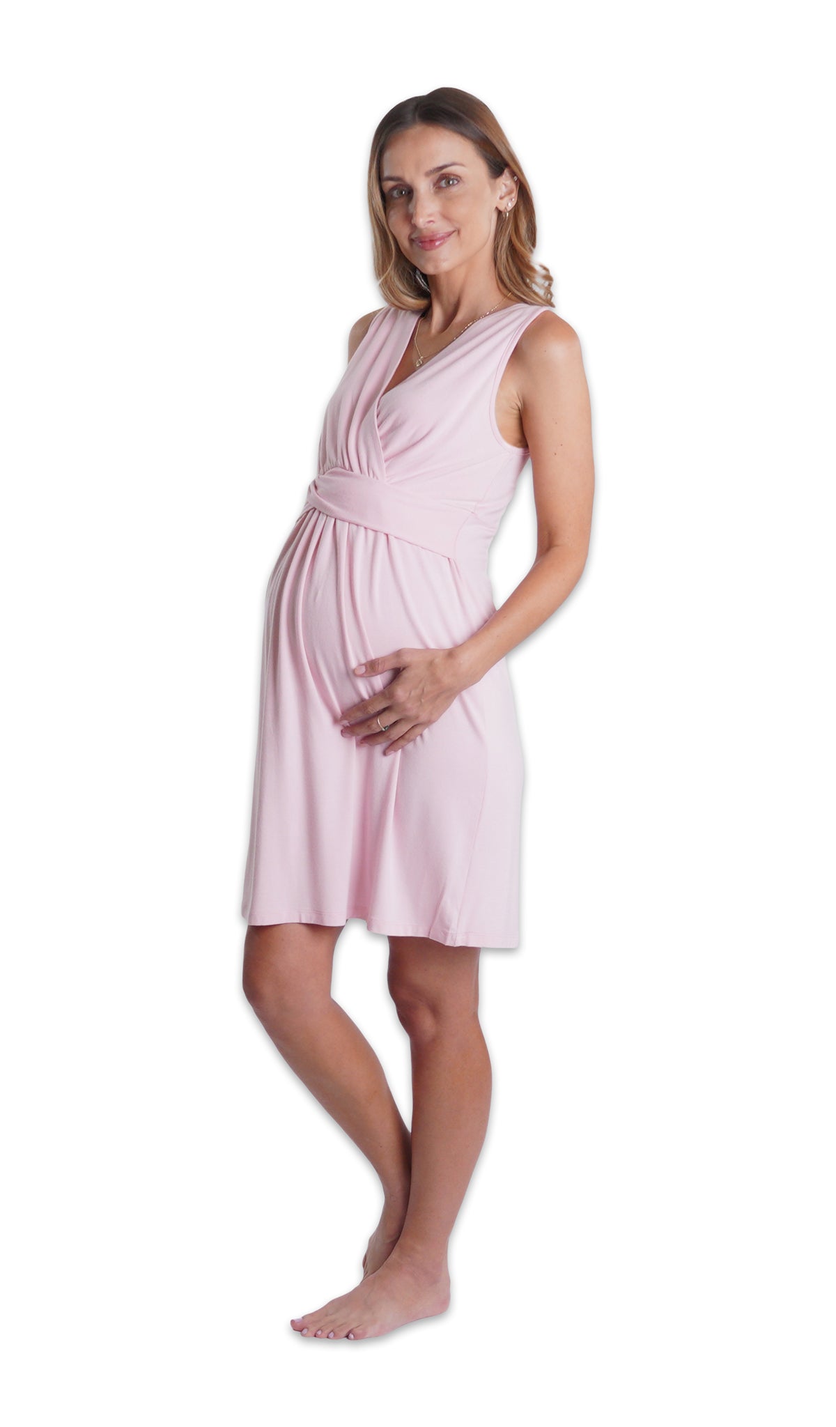 Blush Evie Nightgown. Pregnant woman with one hand on belly, wearing sleeveless nightgown with criss-cross v-neckline and empire waist that falls to knee length. 